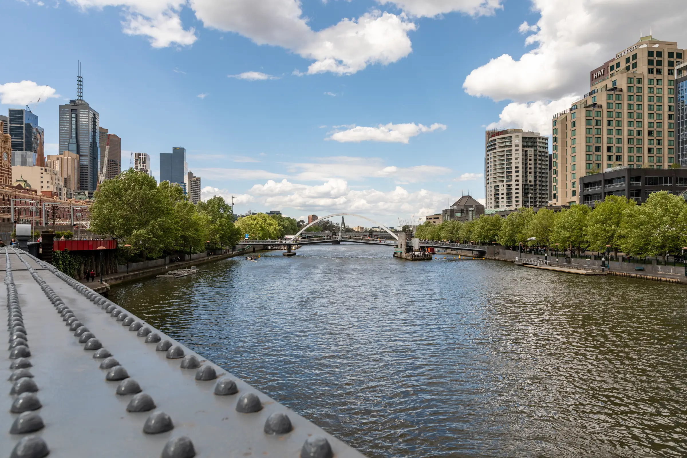The Yarra on a bright day with big white clouds: the river running between tree-lined banks, city towers on both sides